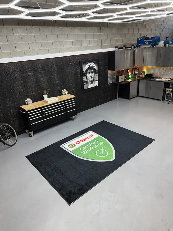 Black indoor logo mat with Castrol logo at a garage entrance